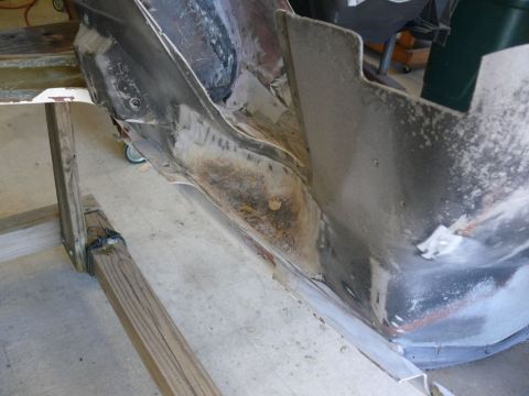 rusted car frame section on wooden support