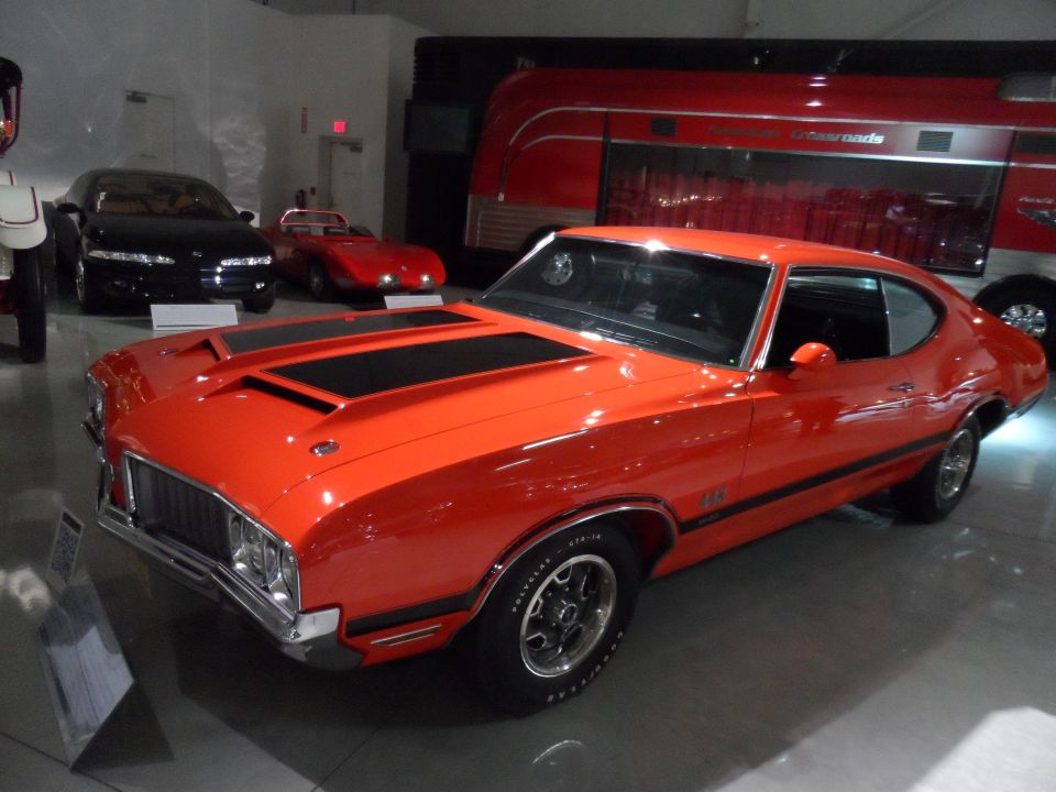 Orange muscle car with black racing stripes, 3/4 front view