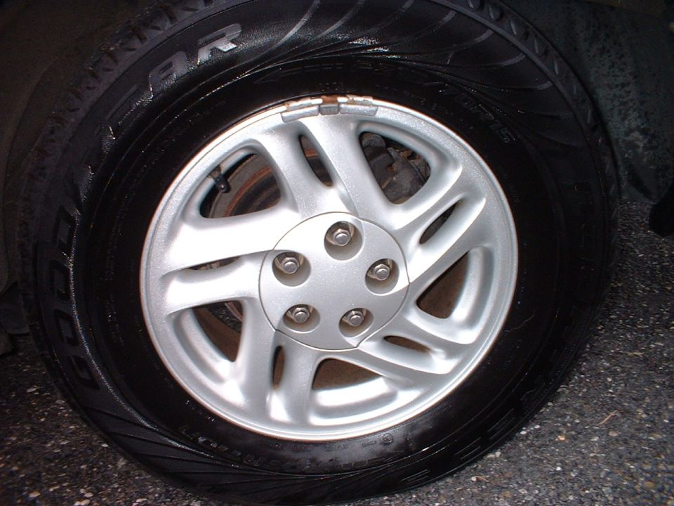 Close-up of silver 5-spoke alloy wheel with Goodyear Eagle tire on a dark car at night