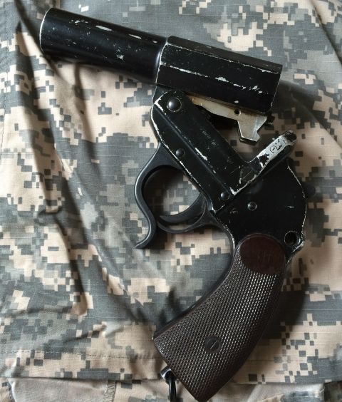 1987 Ford Bronco - A black flare gun rests on a digital camouflage background, with a SuperMotors.net watermark visible.