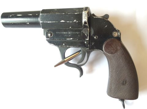1987 Ford Bronco - A black revolver is shown with a brass bullet in its trigger guard, against a white background.