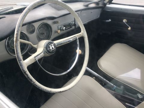 1968 Ford Mustang - The interior of a vintage Volkswagen shows a cracked steering wheel and dashboard, with light-colored seats.