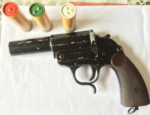 1987 Ford Bronco - A black flare gun and its ammunition are displayed on a white surface.