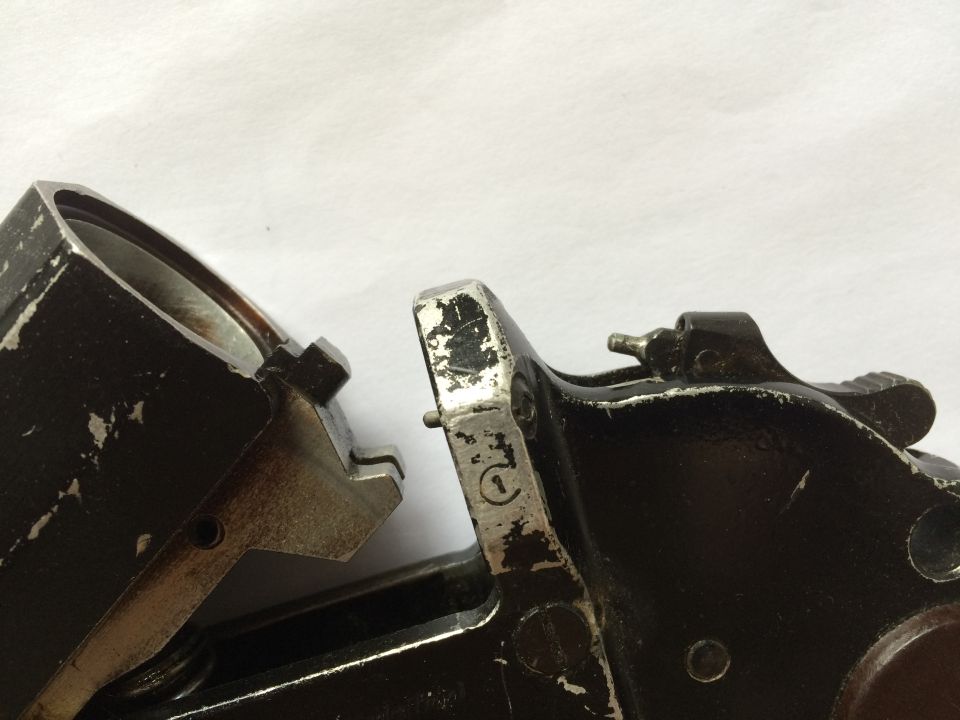Close-up of two interlocking metal mechanical parts, one with a circular stamp