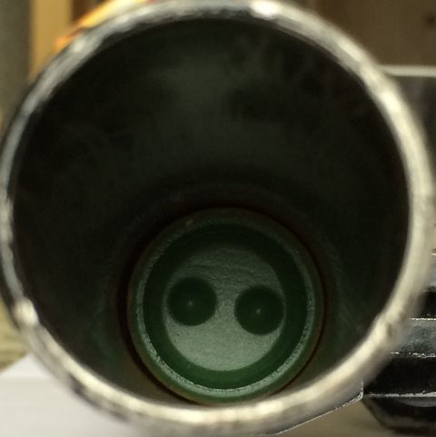 1987 Ford Bronco - Close-up view inside an exhaust pipe reveals a green component with a distinctive dual-opening design.
