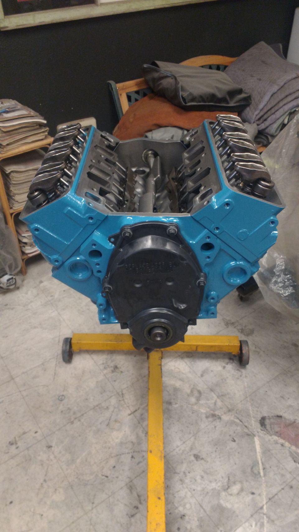 Blue V8 engine on a yellow stand, front view