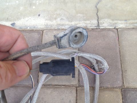 1979 Ford Bronco - A hand holds a dirty electrical connector and frayed wiring harness, with visible text from SuperMotors.net.