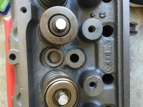 1987 Ford Bronco - Close-up view of an engine cylinder head, showing valve springs, bolts, and stamped markings.
