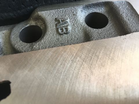 1987 Ford Bronco - A close-up view of a cast metal component, possibly from an engine, showing stamped markings.