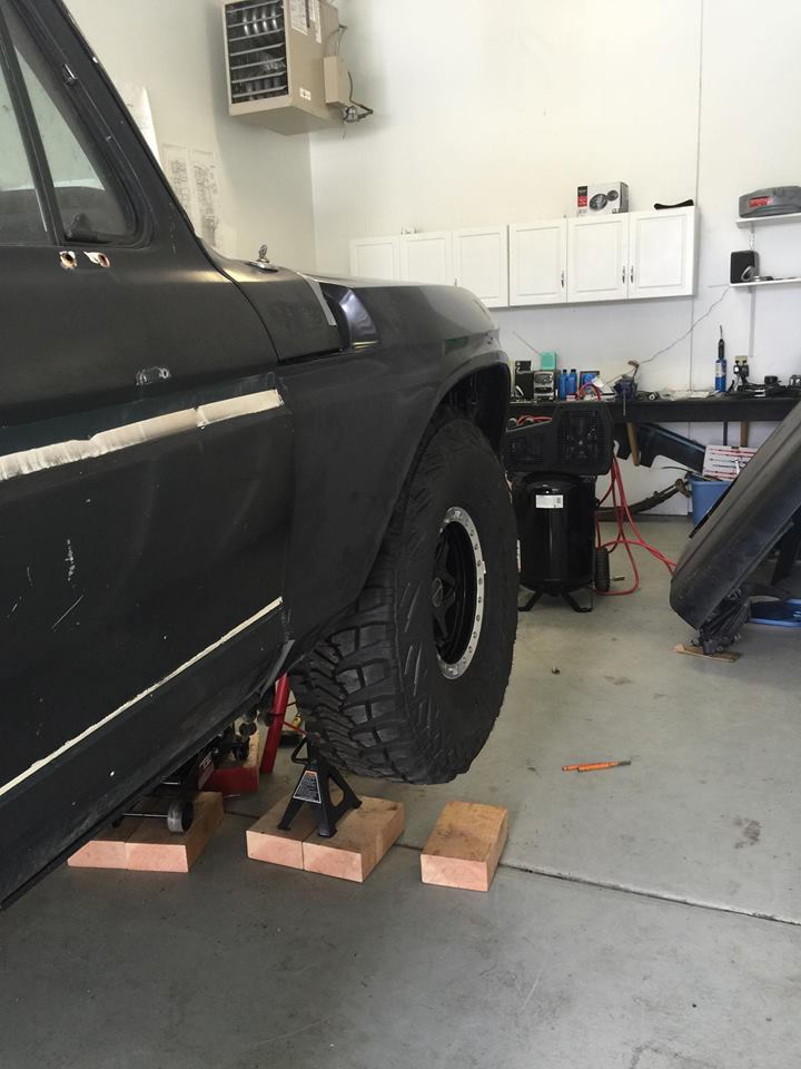 Black SUV fender and large off-road tire on jack stands, showing a portion of the vehicle's side