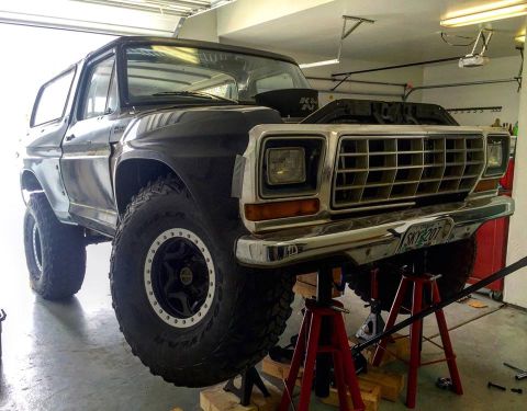 1979 Ford Bronco - 1979 Ford Bronco undergoing maintenance, lifted on jack stands in a garage.