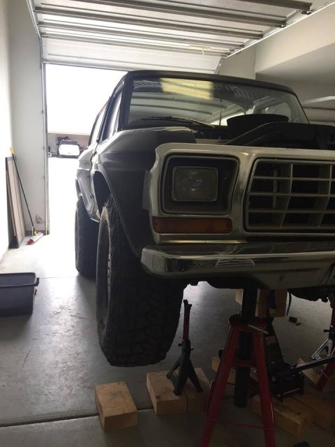 1979 Ford Bronco - Front view of a black 1978 Ford Bronco being worked on in a garage, raised on jack stands.