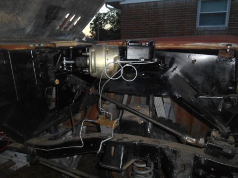 1972 Ford Bronco - Close-up view of engine bay components, including brake booster and master cylinder, with a partially visible rusty hood.
