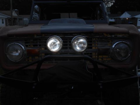 1972 Ford Bronco - The front grille and headlights of a vintage Ford Bronco are visible, with a custom bumper and additional lights.