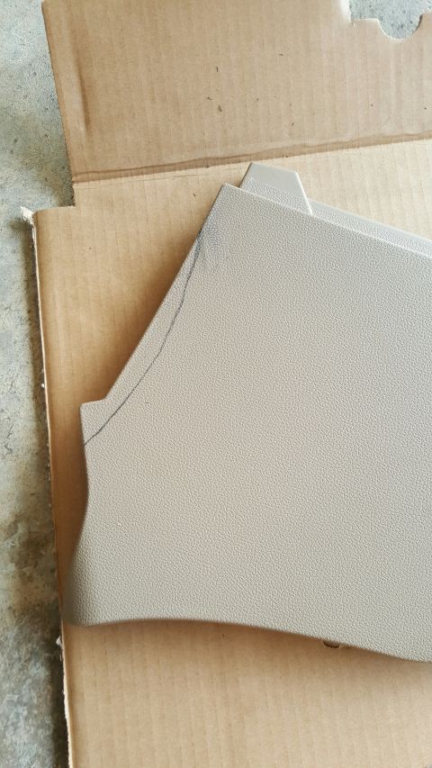 1996 Ford Bronco - A tan interior part, likely from a center console, rests in a cardboard box.