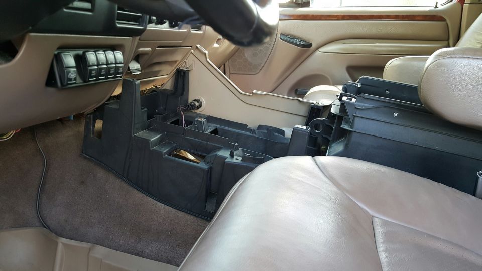 Tan truck interior with the black center console partly disassembled between leather seats