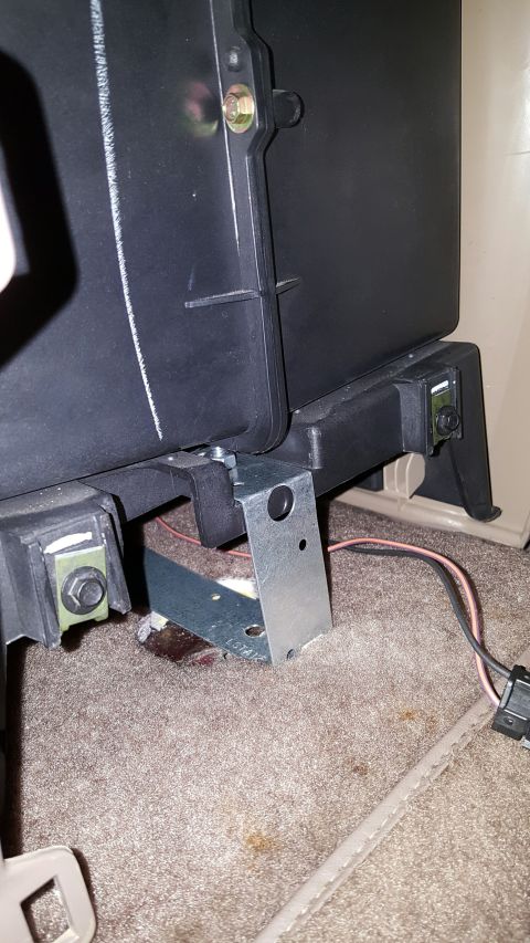 1996 Ford Bronco - Low-angle interior shot of a black seat base bolted to a fabricated steel mounting bracket with yellow-zinc hardware, sitting on tan carpet…