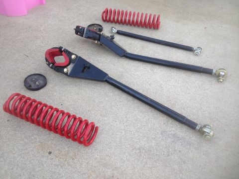 1979 Ford Bronco - Aftermarket suspension components, including coil springs and control arms, are laid out on a concrete surface.