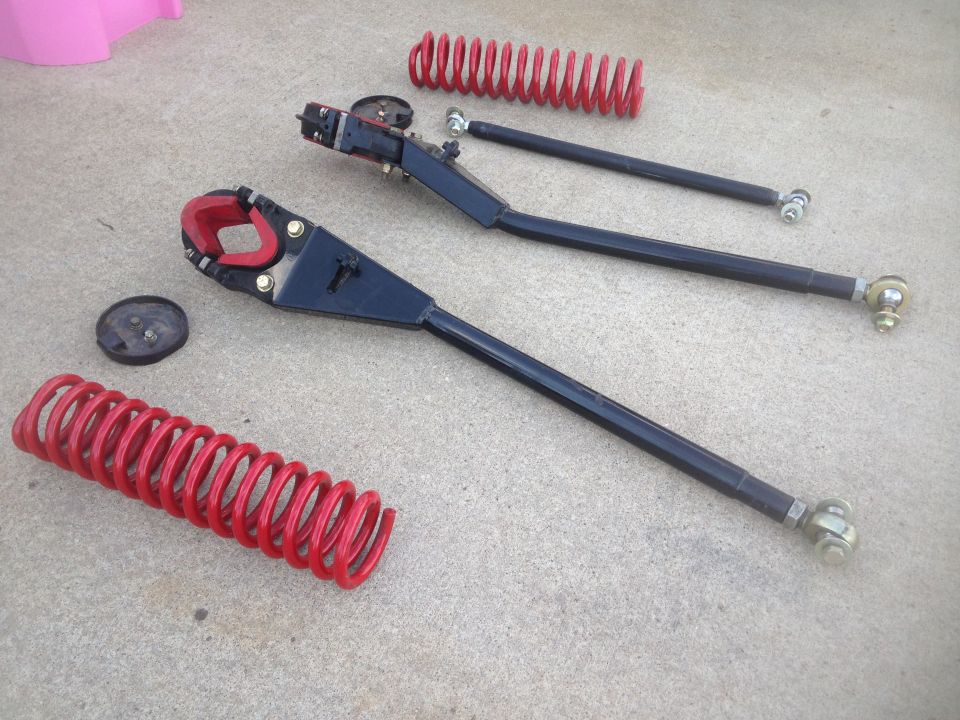 Red coil springs and black suspension control arms with red rubber bushings on concrete