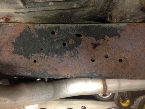 1979 Ford Bronco - Close-up view of a rusted vehicle frame rail and exhaust pipe.