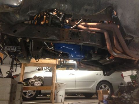 1979 Ford Bronco - Undercarriage view shows exhaust headers and a blue component, with a silver sedan visible beneath.