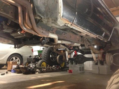 1979 Ford Bronco - Vehicle underbody with exhaust and suspension components visible, with another car in the background.