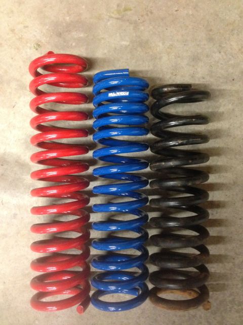 1979 Ford Bronco - Three sets of suspension springs, red, blue, and black, are displayed on a concrete surface.