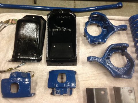 1979 Ford Bronco - Various suspension components, including brake calipers, spindles, and a sway bar, are laid out on a towel.