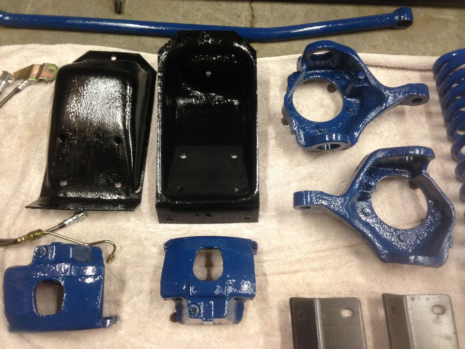 Blue and black suspension parts including brake calipers, spindles, and a sway bar