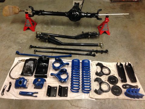 1979 Ford Bronco - Collection of vehicle suspension parts, including a rear axle and springs, ready for installation.
