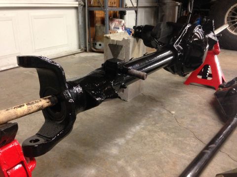 1979 Ford Bronco - A black painted front axle assembly is supported by jack stands and a vise in a garage setting.