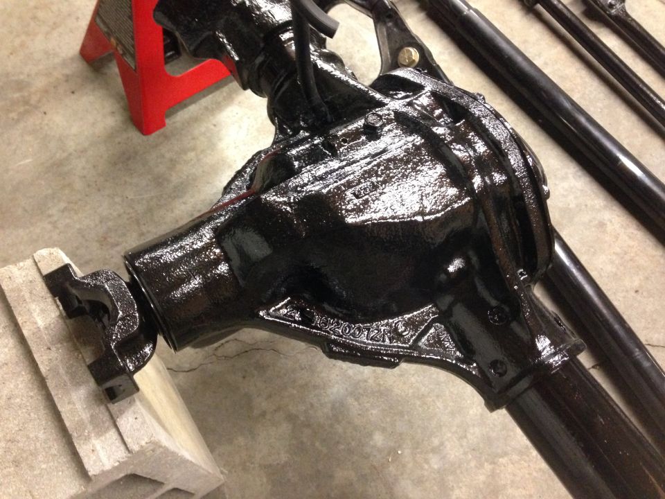Black differential housing on a concrete floor, supported by a red jack stand and concrete blocks