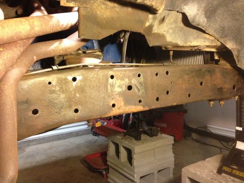 1979 Ford Bronco - Close-up view of a heavily rusted vehicle frame and exhaust manifold, likely undergoing repairs or maintenance.