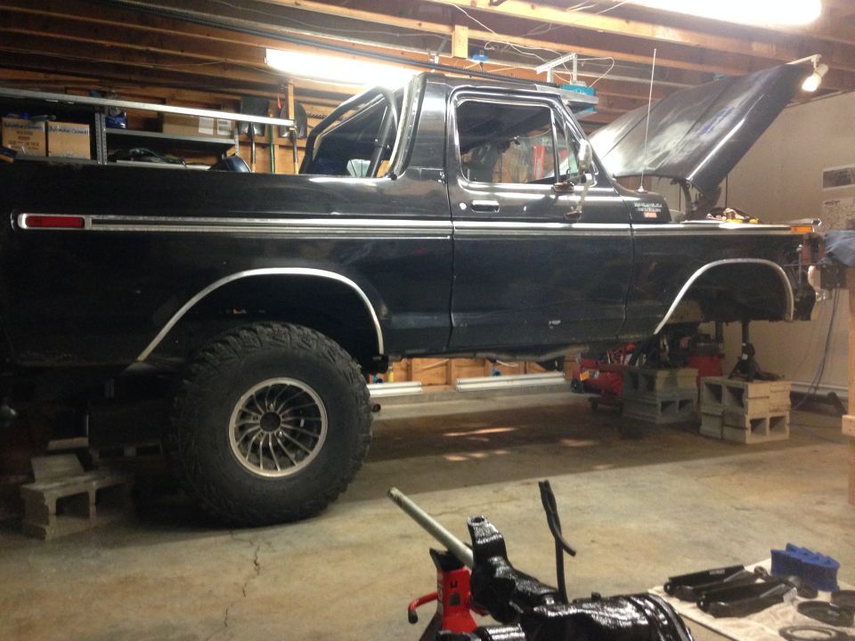 Black Ford Bronco on jack stands in a garage with hood open