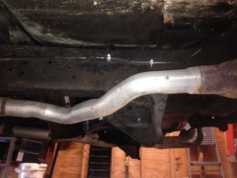 1979 Ford Bronco - The underside of a vehicle displays a section of its exhaust system and frame.