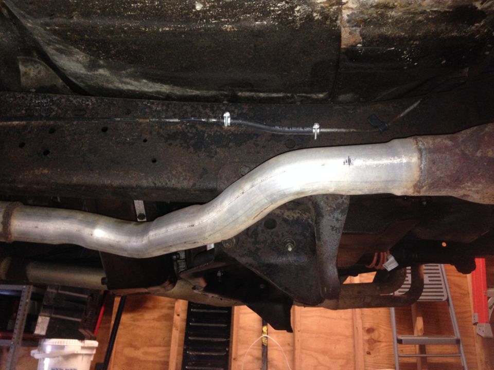 Undercarriage of a vehicle showing rusty frame and exhaust pipes