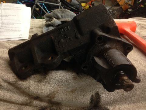 1979 Ford Bronco - A black steering gear box sits on a towel next to an orange mallet.