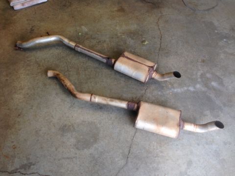 1979 Ford Bronco - A pair of exhaust system components are laid out on a concrete surface.