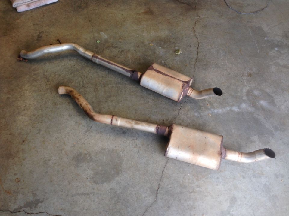 Two exhaust pipes and mufflers on concrete floor