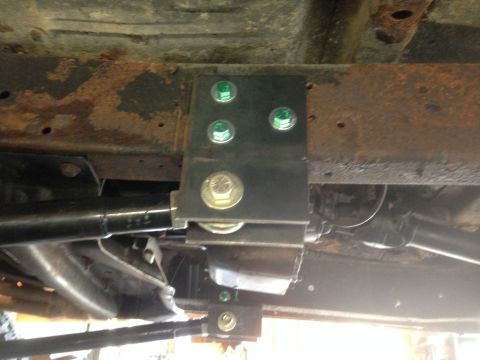 1979 Ford Bronco - Close-up view of a vehicle's undercarriage, highlighting a newly installed suspension component on a rusty frame.