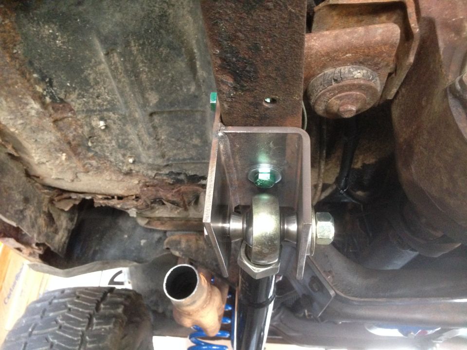 Close-up of a custom suspension bracket attached to rusty frame and a shock absorber