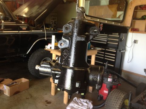 1979 Ford Bronco - A black steering gear box is the focus, with a 1978 Ford Bronco visible in the garage behind it.