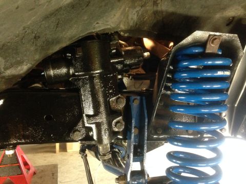 1979 Ford Bronco - Close-up view of the steering box and a bright blue coil spring on the underside of a vehicle.