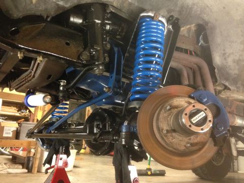 1979 Ford Bronco - Close-up of a vehicle's suspension system bright blue springs and a disc brake assembly with a WARN locking hub.