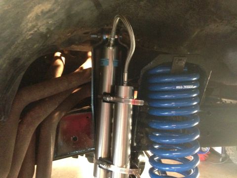 1979 Ford Bronco - Close-up view of suspension components, including a shock absorber and a bright blue coil spring.