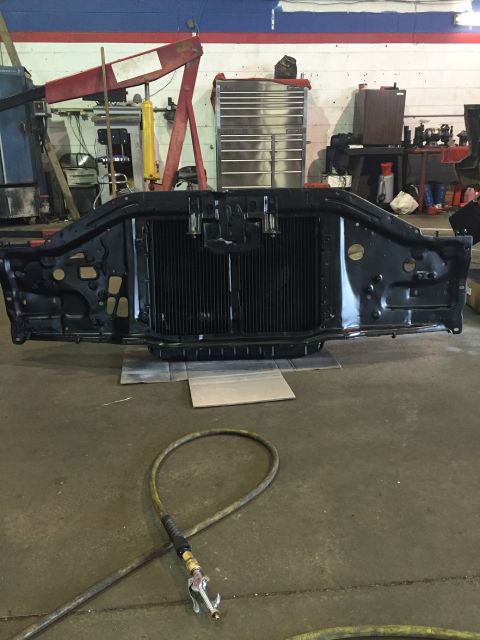 1978 Ford Bronco - A black radiator support assembly, likely for a classic vehicle, sits on the floor of a workshop.