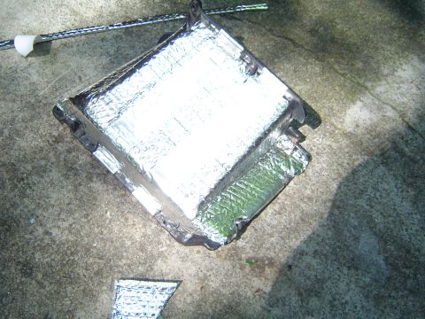 1986 Ford Bronco - A vehicle part with reflective insulation is placed on a concrete surface.