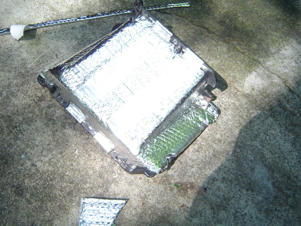 Vehicle part covered in reflective insulation, lying on concrete