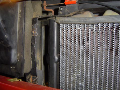1986 Ford Bronco - Close-up view of a vehicle's radiator and surrounding components, showing signs of wear and rust.