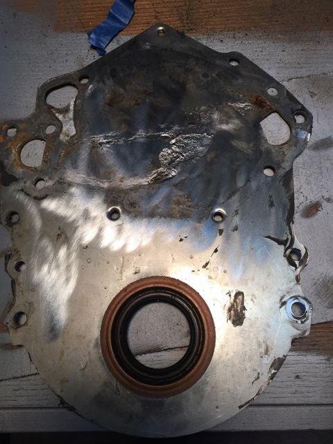 1978 Ford Bronco - A metal engine timing cover, a visible oil seal and signs of wear and repair.